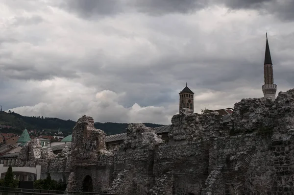 Sarajevo, Bosnia and Herzegovina, 07/08/2018: view of the Sarajevo Clock Tower built by ottoman governor Gazi Husrev-beg, and the minaret of Gazi Husrev-beg Mosque seen from the remains of Taslihan, a 1540 stone inn and  caravanserai