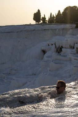 Türkiye, 07/10/2019: Pamukkale 'de Traverten teraslarında (pamuk Kalesi), su ile yatırılan sedimanlı kayanın ünlü doğal sitesi olan kaplıcalardan akan sudan zevk alan bir adam