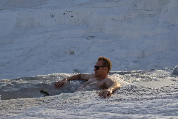 Türkiye, 07/10/2019: Pamukkale 'de Traverten teraslarında (pamuk Kalesi), su ile yatırılan sedimanlı kayanın ünlü doğal sitesi olan kaplıcalardan akan sudan zevk alan bir adam