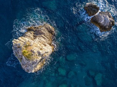 Denizden çıkan kayalarla deniz tabanının havadan görünümü, yukarıdan görülen deniz dibi, şeffaf su