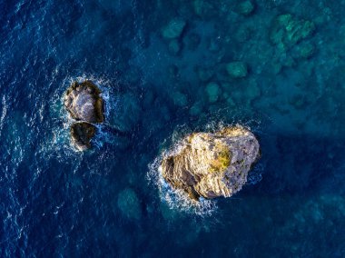 Denizden çıkan kayalarla deniz tabanının havadan görünümü, yukarıdan görülen deniz dibi, şeffaf su