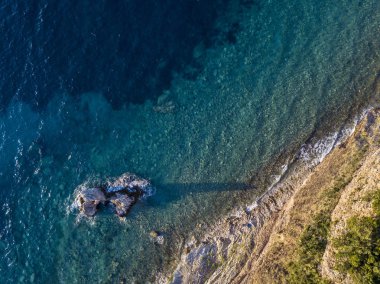 Denizden çıkan kayalarla deniz tabanının havadan görünümü, yukarıdan görülen deniz dibi, şeffaf su