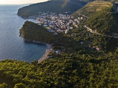 Petrovac kasabası ve Lucice plajının havadan görünüşü, en güzel kumlu plajlardan biri. Gün batımında şemsiyeler ve banyolar. Karadağ