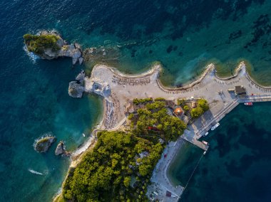 Karadağ 'ın Budva adası Sveti Nikola' nın hava manzarası. Hawaii plajı, şemsiyeler, banyolar ve kristal berrak sular. Şeffaf denize bakan sarp kayalıkları olan sivri kıyılar. Vahşi doğa ve Akdeniz maketi