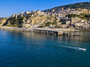 Pizzo Calabro, rıhtım, kale, Calabria, İtalya turizmi. Deniz kenarındaki küçük Pizzo Calabro kasabasının panoramik manzarası. Kayalıklardaki evler. Uçurumun kenarında Aragon kalesi duruyor. Gün batımında deniz önü