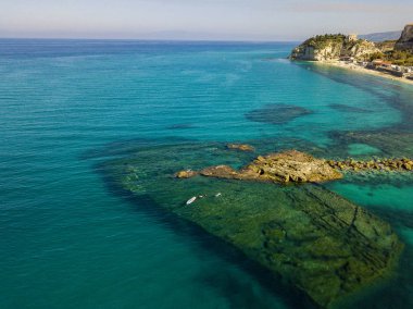 Şeffaf bir denizde yüzen, şnorkelle yüzen bir sörf tahtasının havadan görüntüsü. Denizde yıkanır. Tropea, Calabria, İtalya. Dalış ve yaz tatilleri. İtalyan kıyıları, plajları ve kayaları.