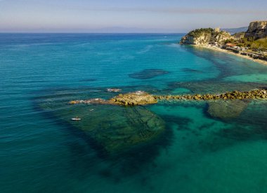 Şeffaf bir denizde yüzen, şnorkelle yüzen bir sörf tahtasının havadan görüntüsü. Denizde yıkanır. Tropea, Calabria, İtalya. Dalış ve yaz tatilleri. İtalyan kıyıları, plajları ve kayaları.