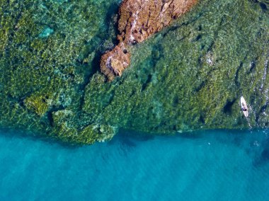 Şeffaf bir denizde yüzen, şnorkelle yüzen bir sörf tahtasının havadan görüntüsü. Denizde yıkanır. Tropea, Calabria, İtalya. Dalış ve yaz tatilleri. İtalyan kıyıları, plajları ve kayaları
