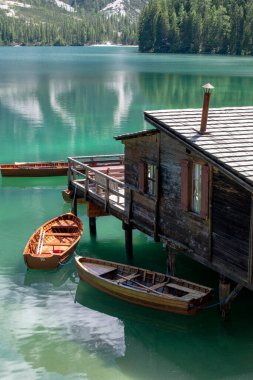 Braies Gölü manzarası, Pragser Wildsee, Prags Dolomites Gölü, Güney Tyrol, İtalya. Ağaçlarla çevrili dağlarla çevrili, ahşap bir kulübenin yakınındaki el değmemiş sularda demirlenmiş kayıkların detayları. Kapsamsız boş hedefler