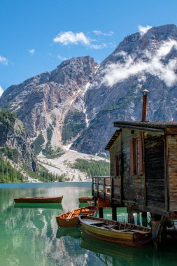 Braies Gölü manzarası, Pragser Wildsee, Prags Dolomites Gölü, Güney Tyrol, İtalya. Ağaçlarla çevrili dağlarla çevrili, ahşap bir kulübenin yakınındaki el değmemiş sularda demirlenmiş kayıkların detayları. Kapsamsız boş hedefler