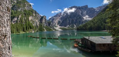 Braies Gölü 'nün panoramik manzarası, Pragser Wildsee, Prags Dolomites Gölü, Güney Tyrol, İtalya. Ağaçlarla çevrili dağlarla çevrili, ahşap bir kulübenin yakınındaki el değmemiş sularda demirlenmiş kayıkların detayları. Kapsamsız boş hedefler