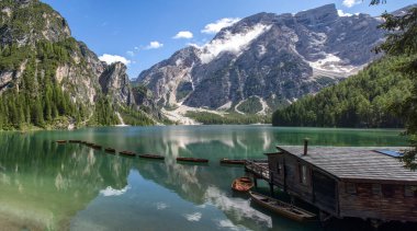 Braies Gölü 'nün panoramik manzarası, Pragser Wildsee, Prags Dolomites Gölü, Güney Tyrol, İtalya. Ağaçlarla çevrili dağlarla çevrili, ahşap bir kulübenin yakınındaki el değmemiş sularda demirlenmiş kayıkların detayları. Kapsamsız boş hedefler