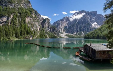 Braies Gölü 'nün panoramik manzarası, Pragser Wildsee, Prags Dolomites Gölü, Güney Tyrol, İtalya. Ağaçlarla çevrili dağlarla çevrili, ahşap bir kulübenin yakınındaki el değmemiş sularda demirlenmiş kayıkların detayları. Kapsamsız boş hedefler