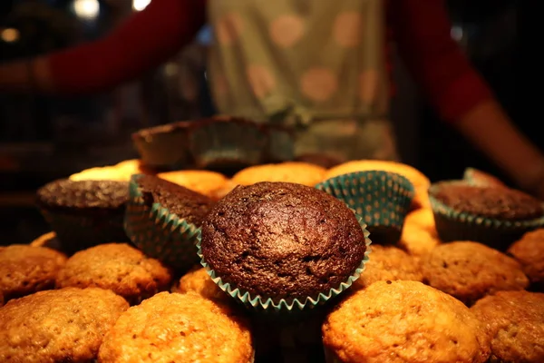 muffins with chocolate and nuts. in the background a cook in an apron