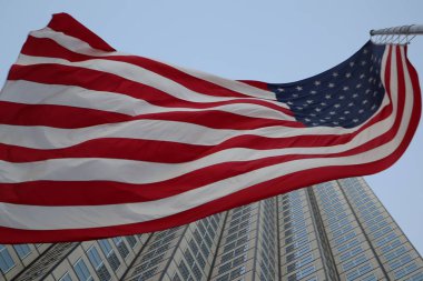 Rüzgara karşı bir gökdelen içinde çırpınan Amerikan bayrağı