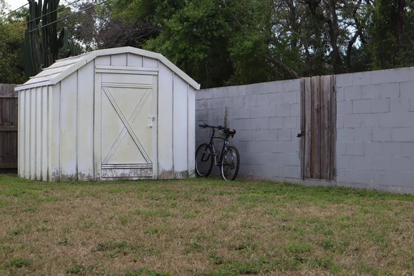 white backyard shed. bicycle at the fence