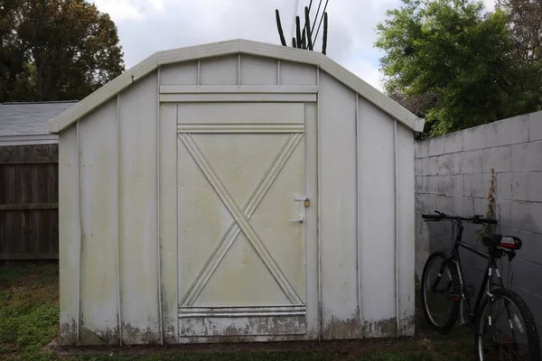 white backyard shed. bicycle at the fence