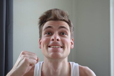 Memnun ifade ile çekici bir genç adam portresi. Beyaz arka plan. duygusal portre. açık tenli ve kısa saçlı. Genç adam kameraya gülümseyen