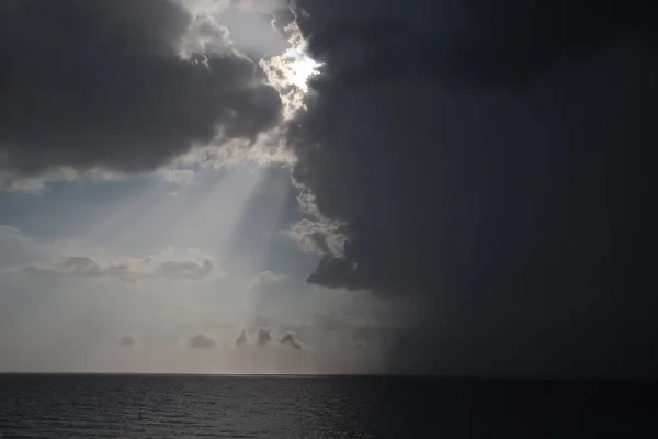 clear sky and storm clouds on the sea. half the sky is clear, half are storm clouds. hurricane coming. storm coming on the ocean, storm clouds on the horizon with ray light