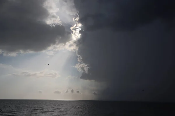 clear sky and storm clouds on the sea. half the sky is clear, half are storm clouds. hurricane coming. storm coming on the ocean, storm clouds on the horizon with ray light