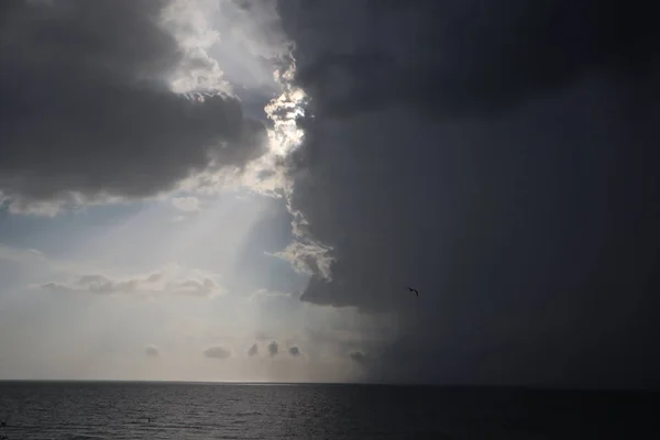 clear sky and storm clouds on the sea. half the sky is clear, half are storm clouds. hurricane coming. storm coming on the ocean, storm clouds on the horizon with ray light