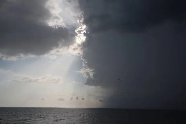 clear sky and storm clouds on the sea. half the sky is clear, half are storm clouds. hurricane coming. storm coming on the ocean, storm clouds on the horizon with ray light
