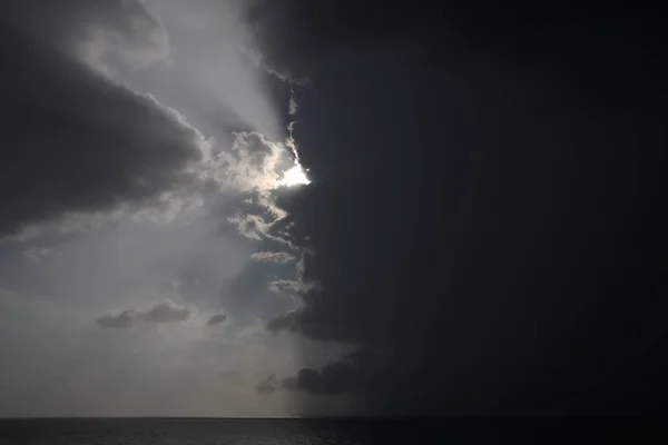 晴朗的天空和风暴云在海上 半边天是晴朗的 一半是暴风雨云 飓风的到来 风暴来到海洋 风暴云在地平线上与射线 — 图库照片