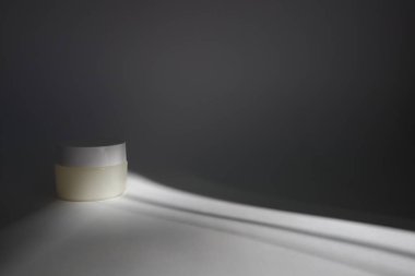 Beyaz arka planda gölgeli yuvarlak kapaklı beyaz plastik bir tüp. Tasarımın için ön görünüm. Yüz estetiği ürünleri. Spa konsepti. Güzellik blogcusu, kuaför tedavisi konsepti. 