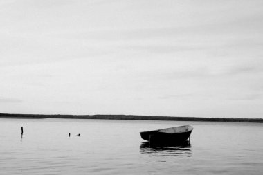 yalnız balıkçı teknesi sakin göle demirledi. durgun bir göl suyunda ahşap balıkçı teknesi. kıyıda demirlemiş ahşap balıkçı teknesi görüntü. metin için alan. Toksovo, Kavgolovo Gölü