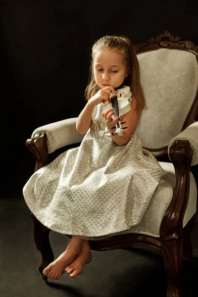 Küçük kemancı, beyaz keman, güzel fotoğraf, karanlık bir arka plan üzerinde.