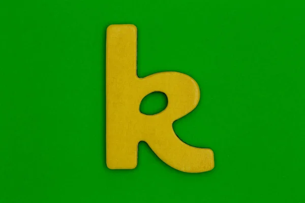 Letter k made of wood painted orange on green background — Stock Photo, Image