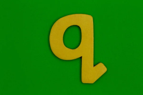 Písmeno q z dřeva malovaná oranžová na zeleném pozadí — Stock fotografie