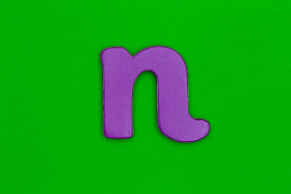 Letter n made of wood painted purple on green background — Stock Photo, Image