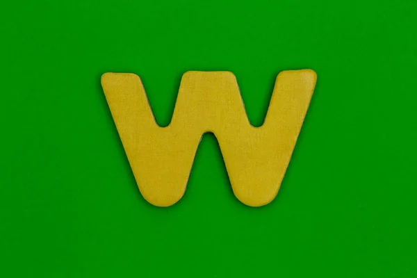 Letter w made of wood painted yellow on green background — Stock Photo, Image