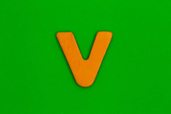 緑の背景にオレンジ色の塗装木で作られた文字 v — ストック写真