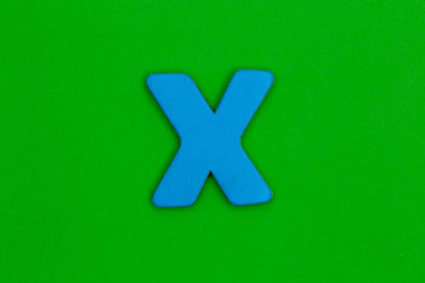 Carta x feita de madeira pintada de azul sobre fundo verde — Fotografia de Stock