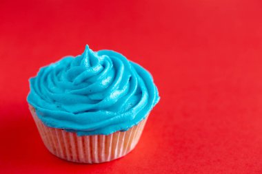 Kırmızı bir tezgah üzerine mavi krema ile cupcake