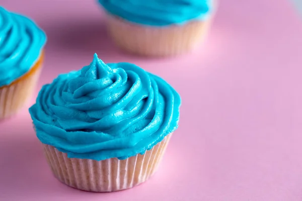 Cupcakes mit blauem Zuckerguss auf einer rosa Arbeitsplatte — Stockfoto