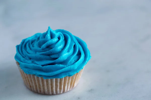 Cupcake con glaseado azul sobre encimera de mármol blanco — Foto de Stock