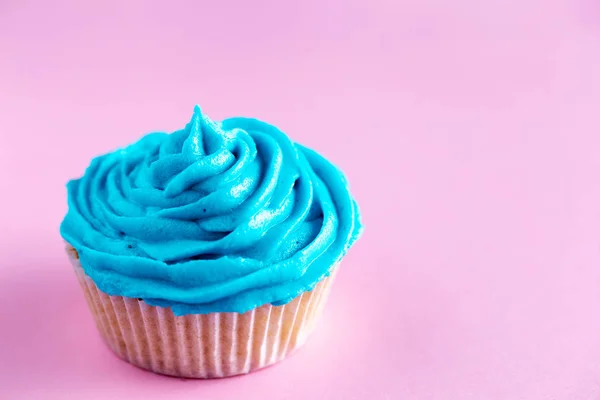 Cupcake mit blauem Zuckerguss auf rosa Arbeitsplatte — Stockfoto