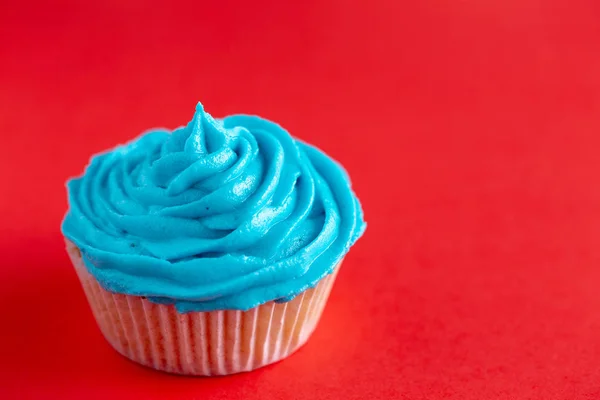 Cupcake mit blauem Zuckerguss auf roter Arbeitsplatte — Stockfoto