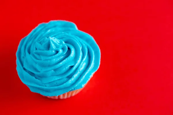 Cupcake mit blauem Zuckerguss auf roter Arbeitsplatte — Stockfoto