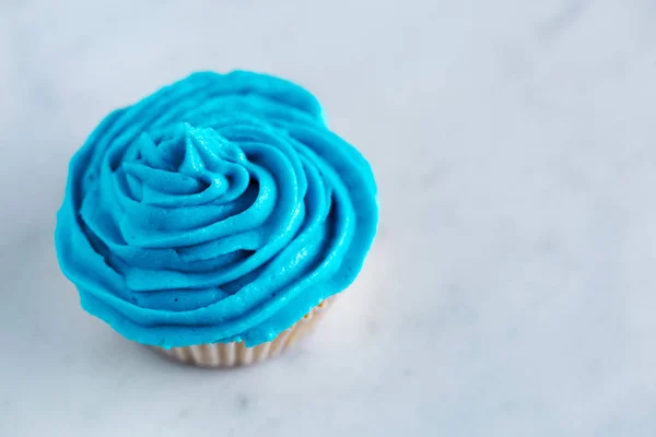 Cupcake con glaseado azul sobre encimera de mármol blanco — Foto de Stock