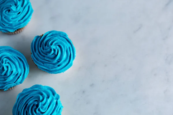 Cupcakes mit blauem Zuckerguss auf einer weißen Marmorarbeitsplatte — Stockfoto