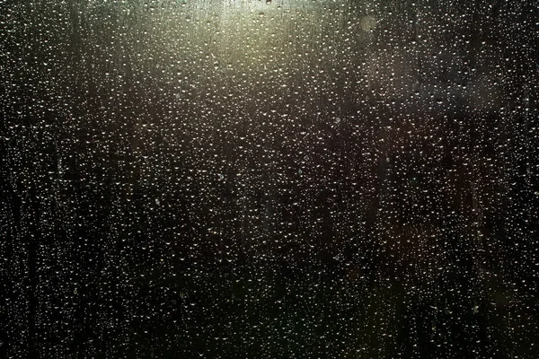 Raindrops on glass window with sun shining through — Stock Photo, Image