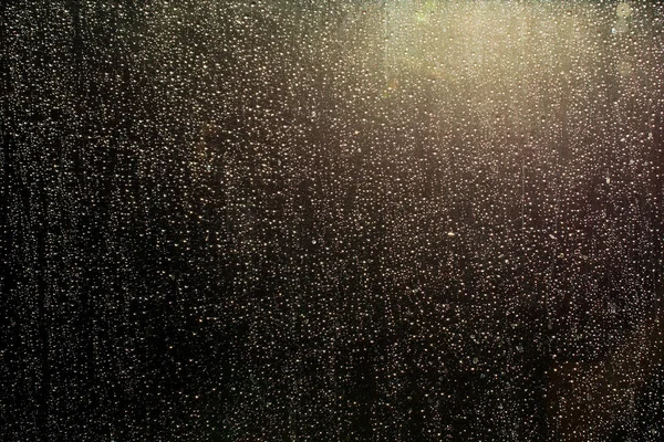 Капли дождя на стеклянном окне, сквозь которые светит солнце — стоковое фото