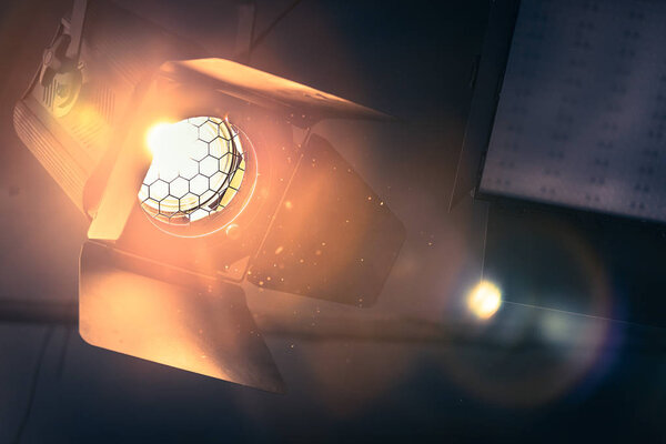 Профессиональный оранжевый студия прожектор висит на потолке. Освещённые пылевые частицы и блики объектива
. 