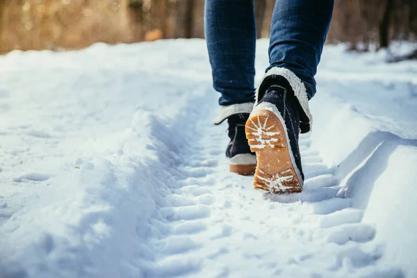 Mujer con botas negras de moda sobre nieve blanca de cerca piernas de mujer  con elegantes botas de cuero de invierno