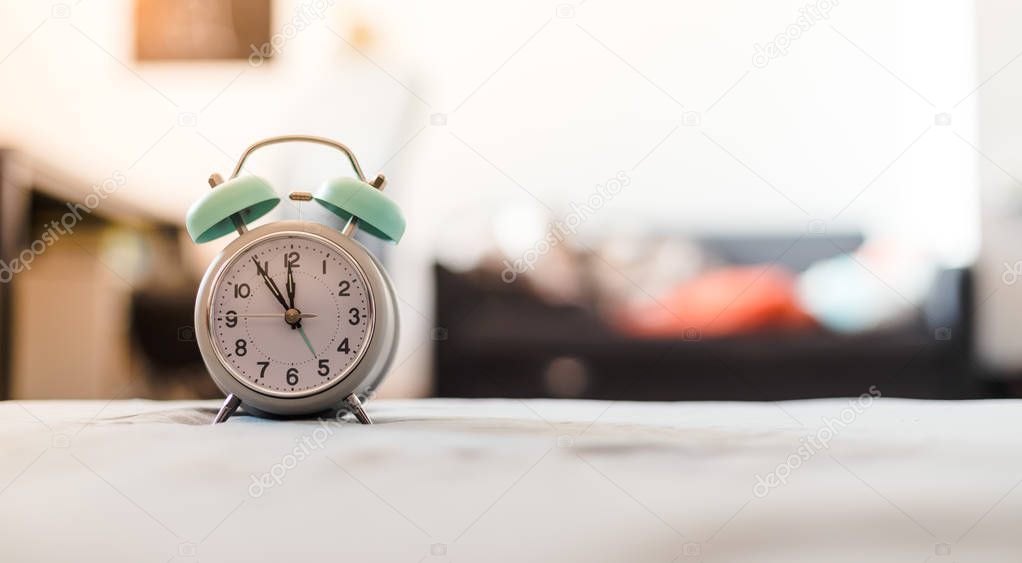 White alarm clock on the bed, morning, copyspace, wake up time