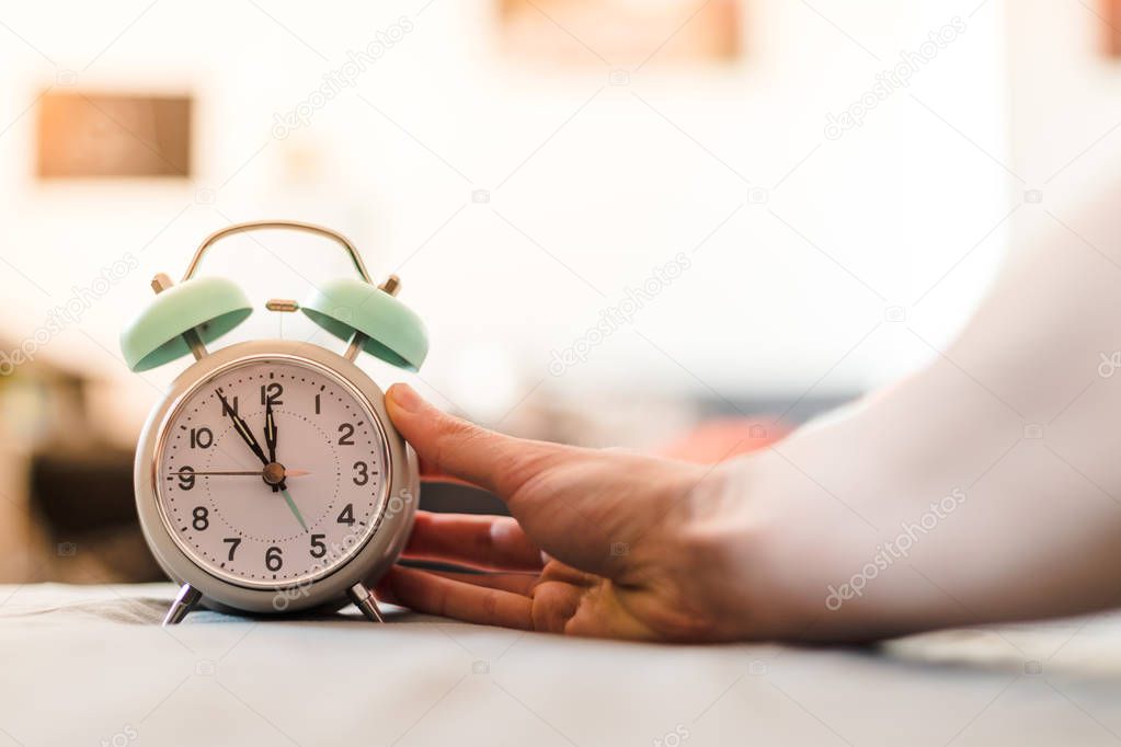 Man is pushing an alarm clock, sunshine in the morning, blurry background